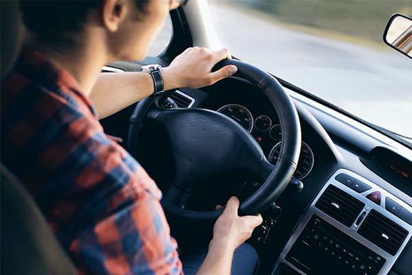 Teenage boy in flannel driving a car.